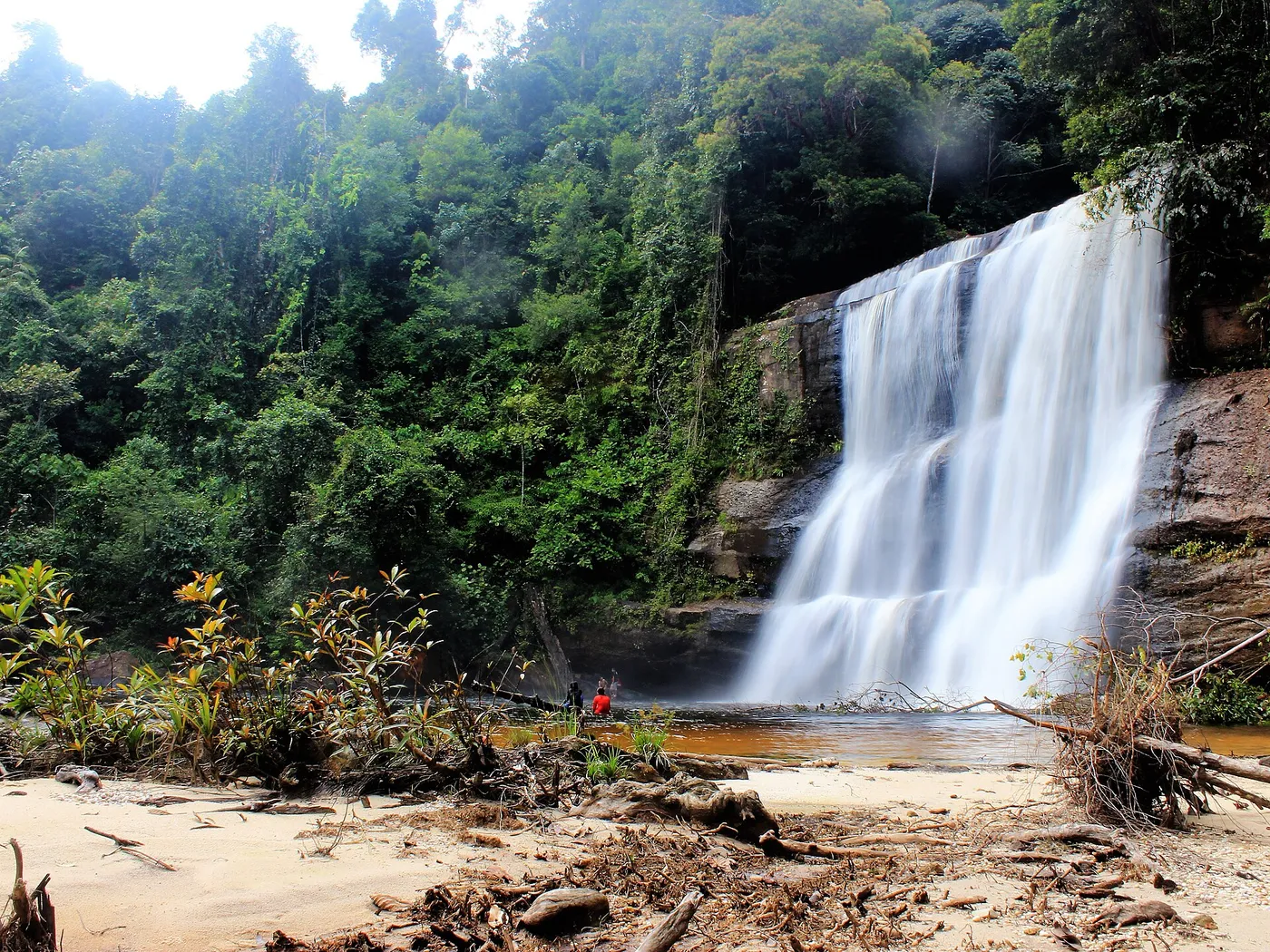 A broad waterfall above a pale sandy bank in the rainforest at Riam Dait, West Kalimantan.