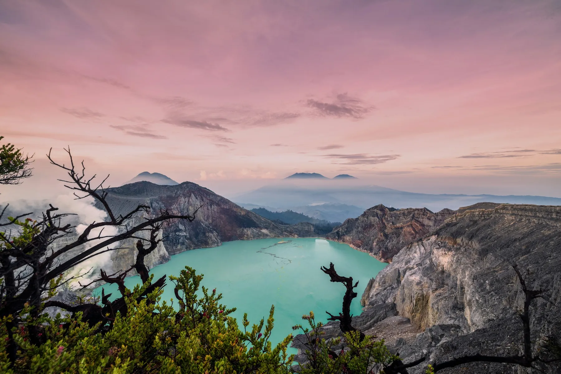 The turquoise lake at Ijen with a pink sky at dawn